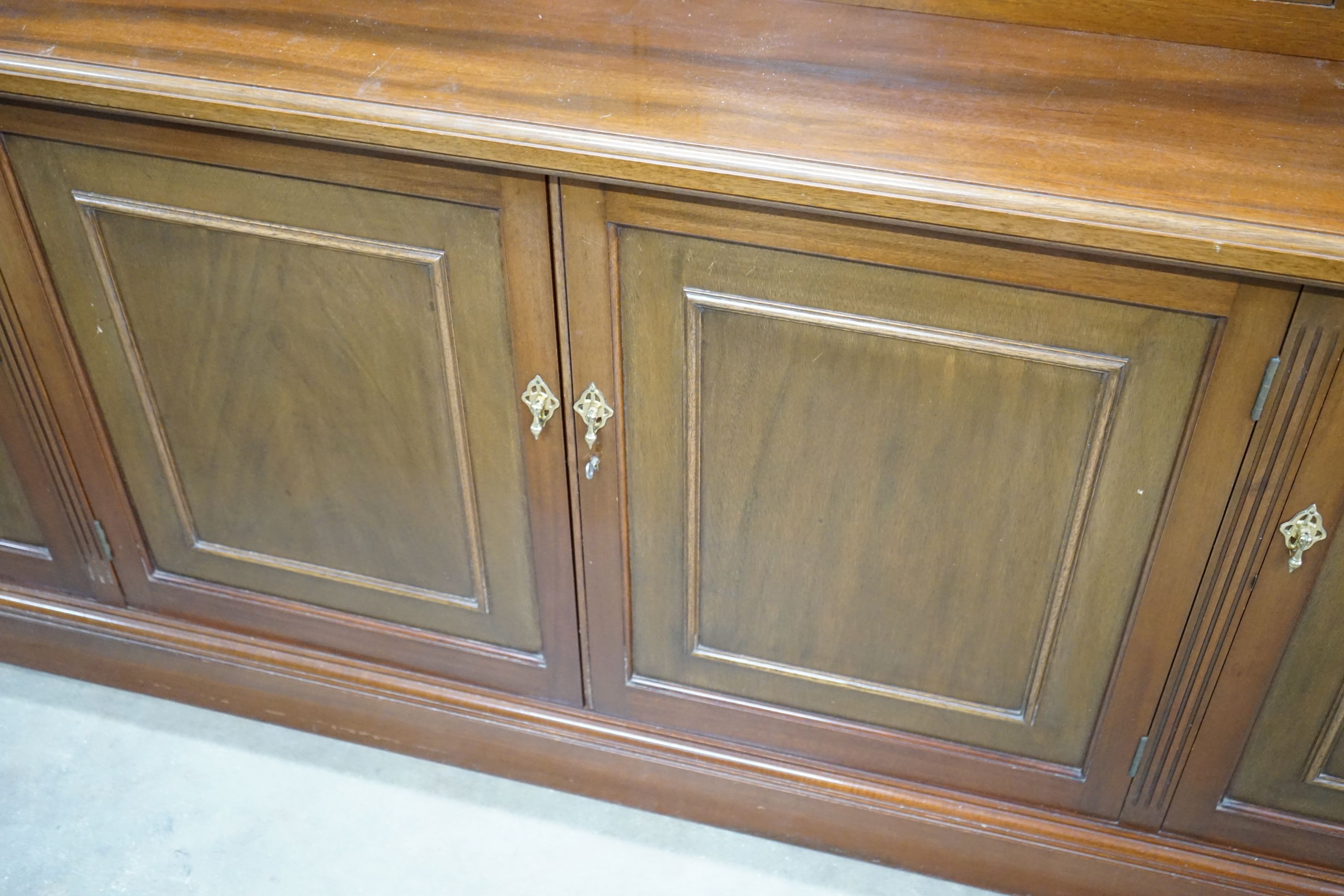 A Victorian style four section mahogany library bookcase, the upper section fitted clear glazed doors above further panelled doors on plinth base, length 216cm, depth 51cm, height 215cm